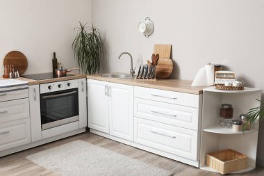 Beyaz tezgahlı, fırınlı ve lavabolu modern mutfağın içi.