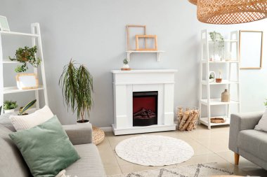 Şömineli ve gri kanepeli, aydınlık oturma odasının içi.