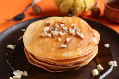 Turuncu arka planda bal ve fındıklı lezzetli balkabaklı gözleme tabağı, yakın plan.