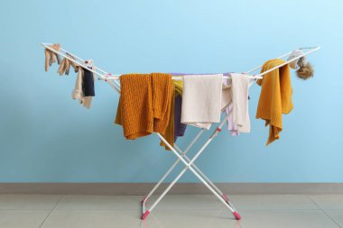 Mavi duvarın yanındaki kurutucuda asılı temiz kışlık giysiler.