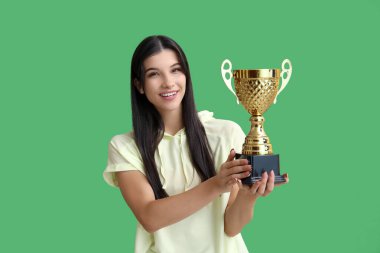 Yeşil arka planda altın kupası olan genç bir bayan.