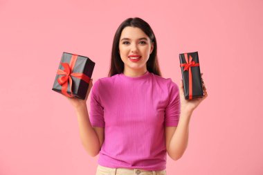 Pembe arka planda hediye kutuları olan güzel bir genç kadın. Kara Cuma indirimi