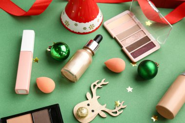 Yeşil arka planda farklı makyaj ürünleriyle Noel kompozisyonu