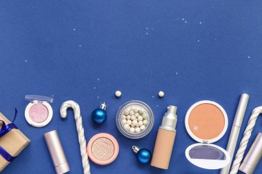 Mavi arka planda farklı makyaj ürünleri olan Noel kompozisyonu