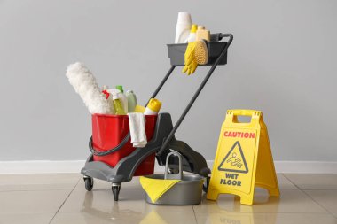 Tramvay temizlik malzemeleri ve uyarı levhası ile aydınlık duvarın yanında.