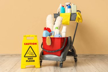 Temizlik malzemeleri ve bej duvarın yanında uyarı levhası olan bir araba.