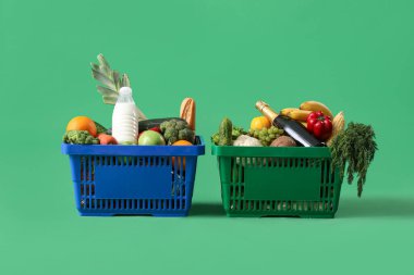 Yeşil arka planda yiyecek dolu alışveriş sepetleri.
