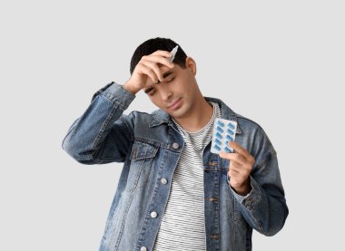 Nazal damlaları ve hafif arka planda hapları olan hasta genç bir adam.