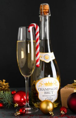 Bir şişe şampanya, cam ve arka planda güzel Noel süslemeleri.