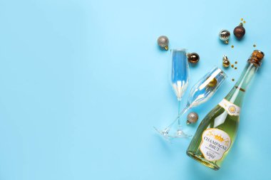 Renkli arkaplanda şampanya, bardak ve Noel toplarıyla kompozisyon