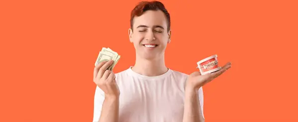 Young Man Holding Jaw Model Braces Money Orange Background — Stock Photo, Image