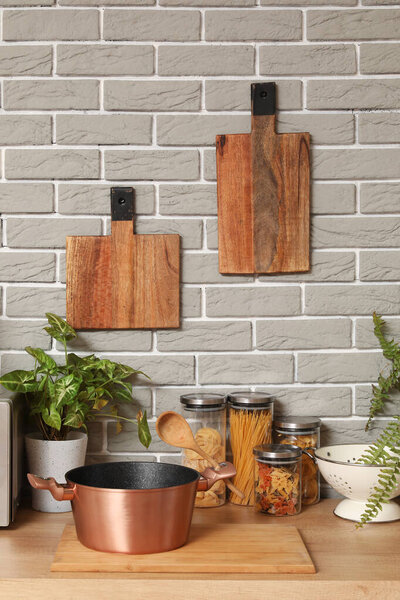 Деревянная столешница с кухонными принадлежностями, комнатные растения и посуда на современной кухне