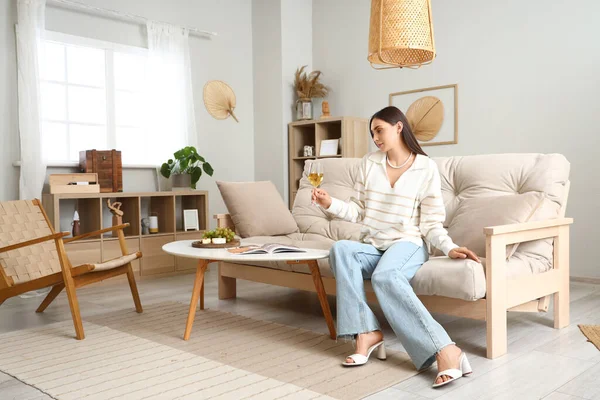 stock image Young woman with glass of wine sitting on couch at home