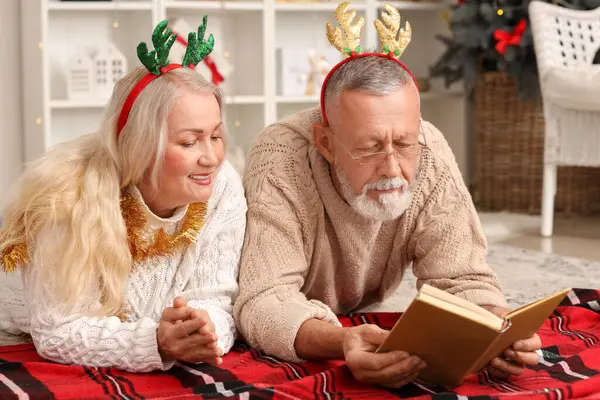 Mutlu yetişkin çiftler Noel arifesinde evde kitap okuyor.