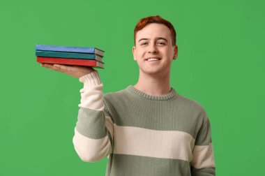 Elinde yeşil arka planla ilgili kitaplar tutan genç adam
