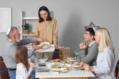 Genç bir kadın Hanuka 'da ailesiyle yemek yiyor.