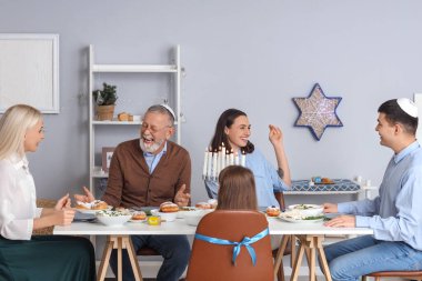 Mutlu genç bir kadın Hanuka 'da ailesiyle yemek yiyor.