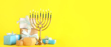 Hanukkiah 'ın hediyeleri ve sarı arka plandaki dreidelarla metin için yeri var. Hanuka kutlaması