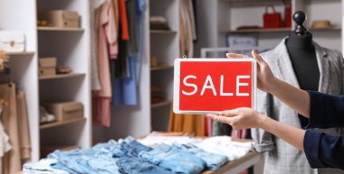 Modern giyim mağazasında metin satışı yapan kadın satıcı panosu