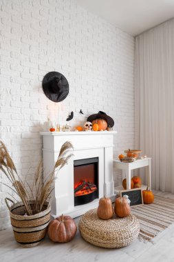 Beyaz tuğla duvarın yanında Cadılar Bayramı süslemeleri ve balkabaklarıyla şömine