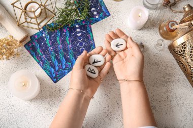 Rünleri olan cadı, tarot kartları ve grunge masasında yanan mumlar.