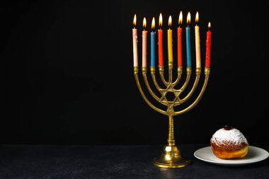 Siyah arka planda Hanuka için şamdanlı ve lezzetli donutlu Menorah.