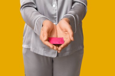 Sarı arka planda prezervatifli güzel bir genç kadın, yakın plan. Güvenli seks konsepti