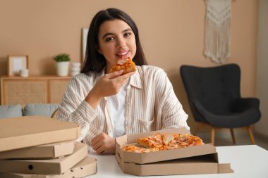 Evde lezzetli bir pizza ve karton kutuyla genç bir kadın var.