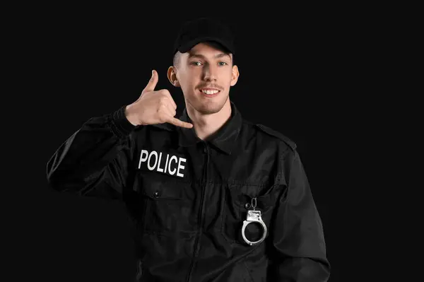 Młody Policjant Pokazujący Gest Zadzwoń Mnie Ciemnym Tle — Zdjęcie stockowe