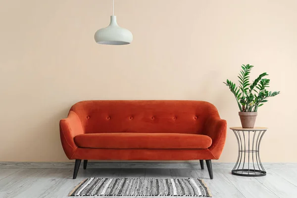 Interior of stylish living room with red sofa, plant and lamp