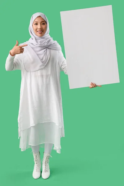 Schöne Muslimin Zeigt Auf Leeres Plakat Auf Grünem Hintergrund — Stockfoto