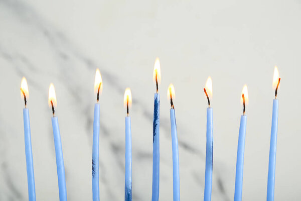Burning candles for Hanukkah celebration on light background, closeup