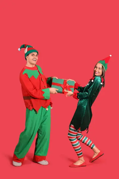 Glückliches Paar Elfenkostümen Mit Geschenkbox Auf Rotem Hintergrund — Stockfoto