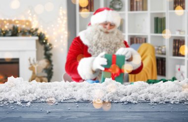 Noel Baba ve Noel hediyesiyle oturma odasında boş ahşap masa.