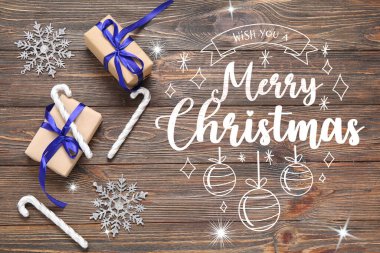 Güzel Noel süsleri ve ahşap arka planda hediyeleri olan tebrik kartı.