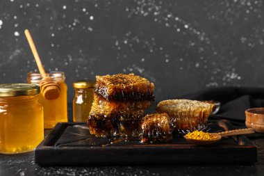 Tatlı bal, taraklar ve siyah arkaplanda arı poleni