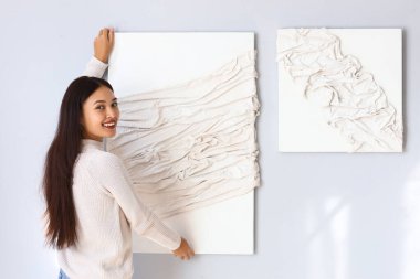 Genç Asyalı kadın evdeki ışık duvarına 3 boyutlu resim asıyor.