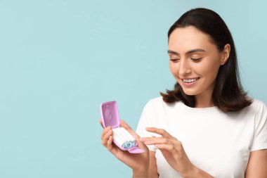 Mavi arka planda tampon saklama kutusu olan güzel genç bir kadın.