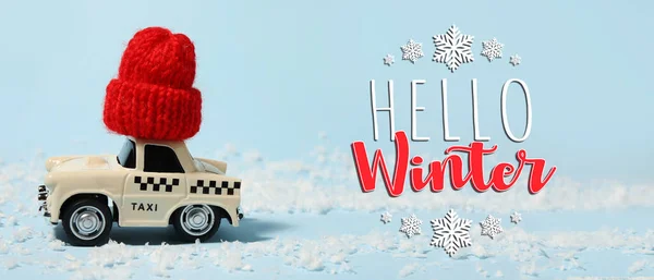 Banner with text HELLO WINTER and small car toy with knitted hat