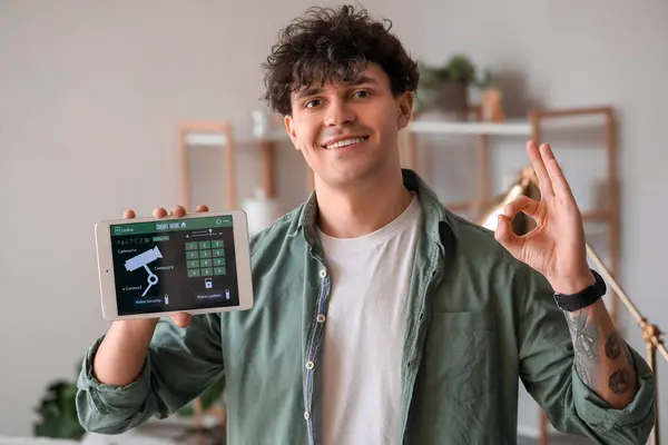 Young man with smart home security system control panel showing OK