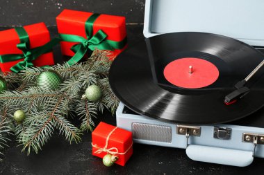 Koyu arkaplanda Noel süslemeleri ve hediyeleri olan klasik turntable.