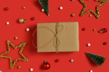 Kırmızı arka planda hediye kutusu ve dekoru olan Noel kompozisyonu.