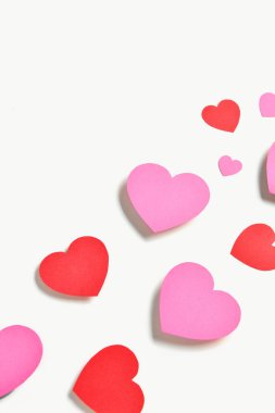 Romantik kompozisyon, beyaz arka planda kırmızı ve pembe kağıt kalpler. Sevgililer Günü.