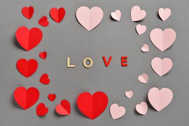 Gri arka planda kırmızı ve pembe kağıt kalplerle romantik kompozisyon. Sevgililer Günü.