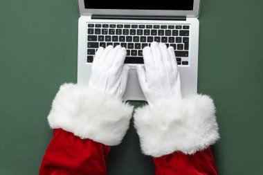 Noel Baba elleri modern dizüstü bilgisayarla arka planda, yakın plan