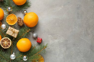 Köknar dallı lezzetli portakallar ve gri arka planda Noel topları