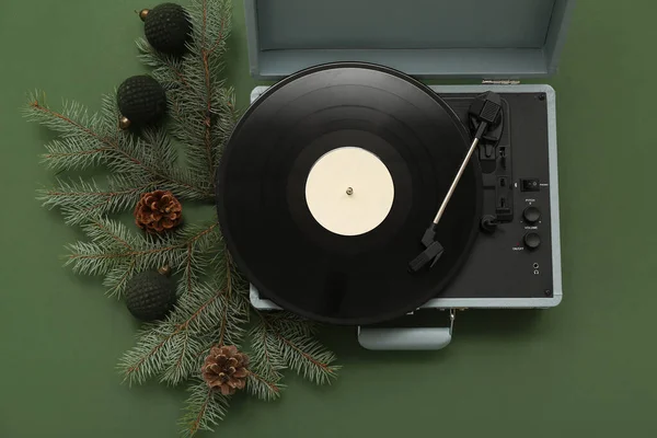 Vintage record player with vinyl disc and Christmas decorations on green background
