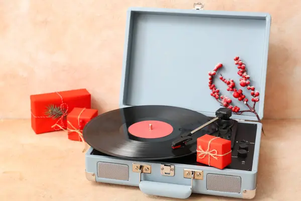 Vintage record player with festive decorations and gifts on beige grunge background