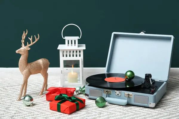 Vintage record player, Christmas gifts and decorations on floor near color wall
