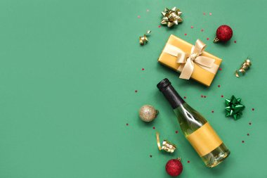 Yeşil arka planda Noel dekoru olan şampanya şişesi.